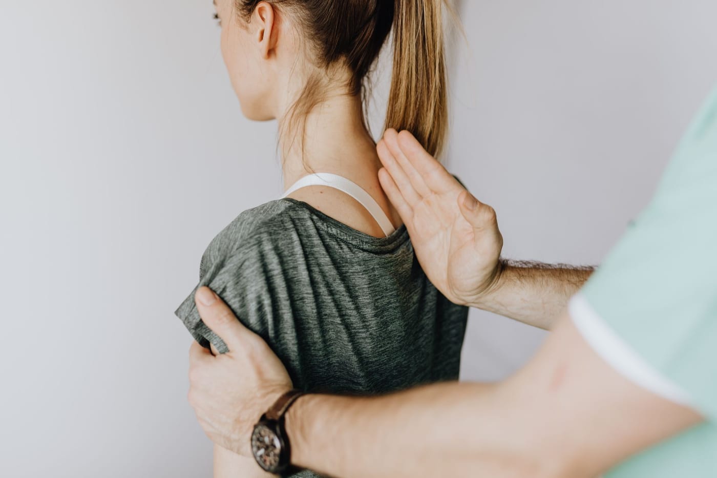 A clinician assessing a patient's shoulder and neck