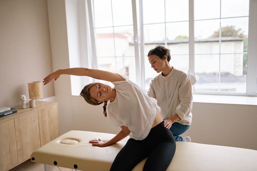 A therapist guiding a patient through a seated side stretch