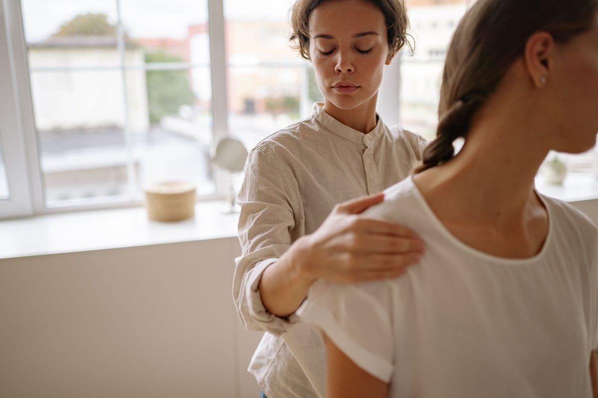 A physiotherapist assessing a patient's shoulder range of motion in a bright treatment room