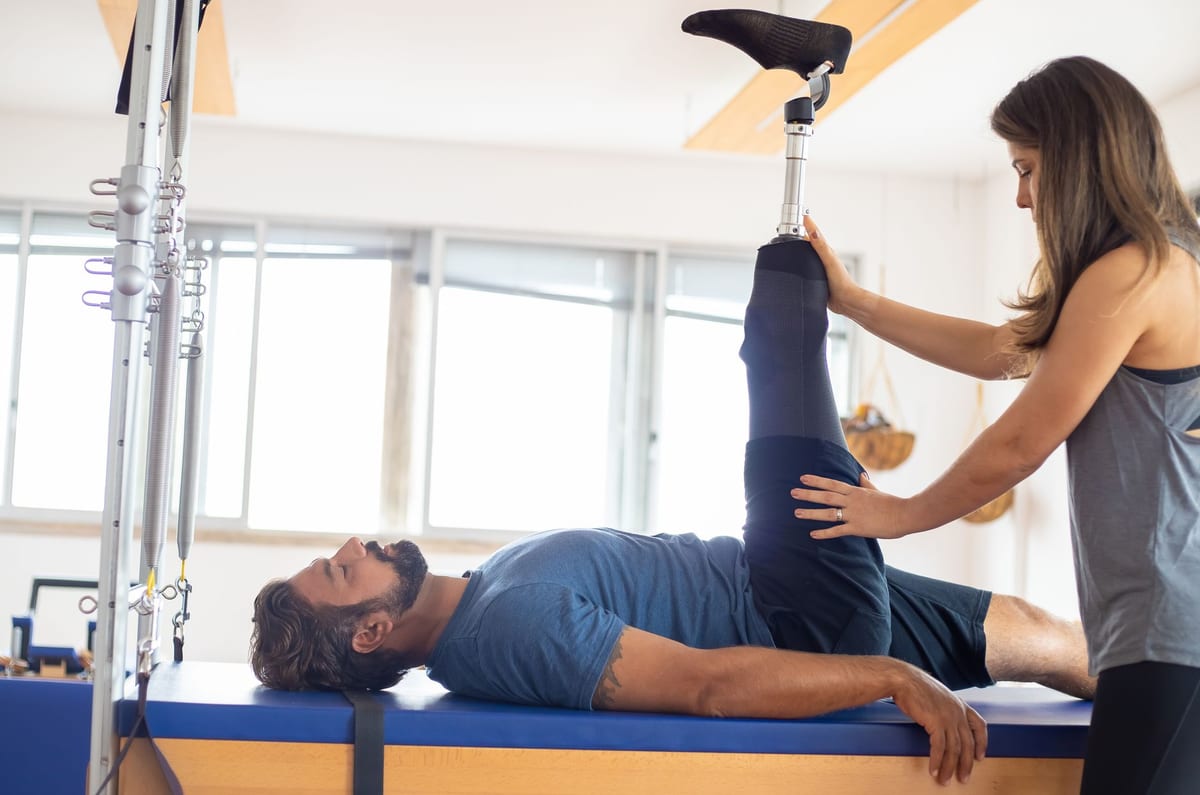 A therapist supporting a patient through a guided leg movement on rehabilitation equipment